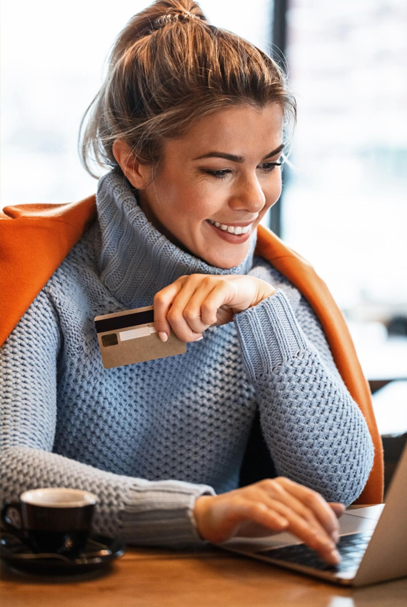 E-commerce nacional: mulher usando notebook e segurando um cartão de crédito
