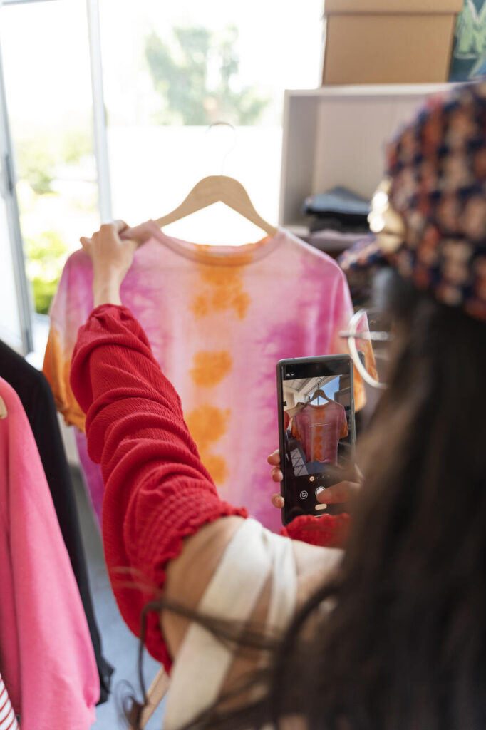 Tendências de marketing digital: mulher usando smartphone para tirar foto de camiseta