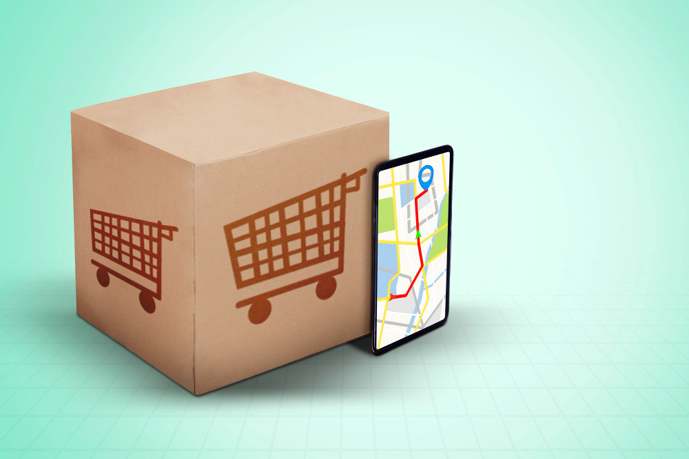 Caixa de entrega de e-commerce com carrinho de compras com um smartphone ao lado indicando uma localização, representando o alto custo do frete.