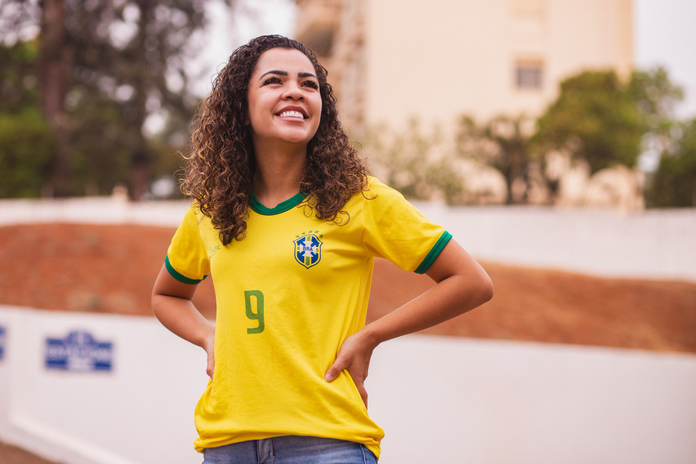 Mulher sorridente vestindo camisa da Seleção Brasileira de Futebol representando a Moda e Copa do Mundo 2026
